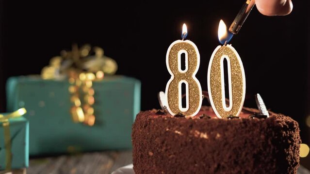 Number eighty birthday candle on sweet cake on the table, 80th birthday. Fire from the lighter, blow out the holiday candle.