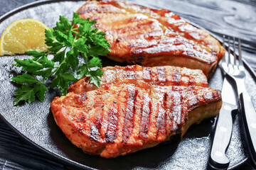 grilled bone-in pork chops on a black plate