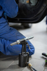 Car mechanic in car service with tools for repairing dents in car body. 