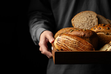 Man holding wooden tray of assorted variety of bread