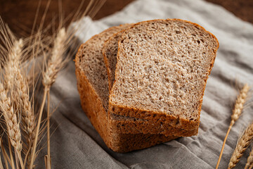 Fresh baked sliced loaf of rye bread on a brown background