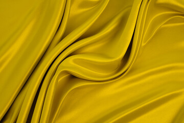 Beautiful smooth elegant wavy golden mustard yellow satin silk with yellow monochrome background design. Luxury cloth fabric texture.