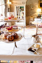 A cake stand full of delicious fancy cakes and sandwiches for an English high tea in a stately home.