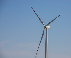 wind mill or also wind-turbine on wind farm in rotation to generate electricity energy on outdoor with sun and blue sky, conservation and sustainable energy concept