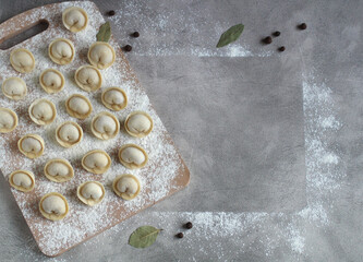 homemade dumplings on a cutting board in rows of flour, pepper and bay leaf