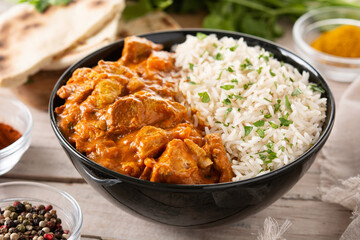 Indian butter chicken in black bowl on wooden table