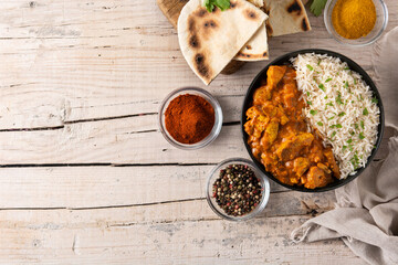Indian butter chicken in black bowl on wooden table. Top view. Copy space