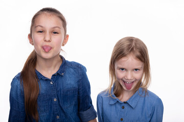 Two kid girls 6 and 8 years old with wide open mouth and shows tongue and grimaces. Child wearing a...