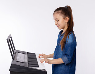 Home lesson of music. Cute girl learning to play piano keyboard synthesizer on white background. Studying the music at home