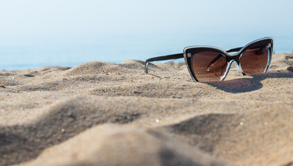 Fototapeta na wymiar Sunglasses on the beach. Relaxation Vacation Travel - Blue Sea, White Sand, Shining Sun on the Beach