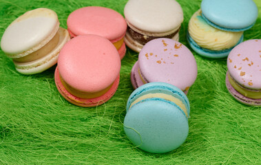 baked macarons with different flavors on a green background, top view