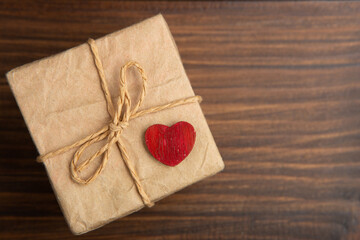 Valentine's Day greetings concept. Little red wooden crafted heart and gift box close up on the...