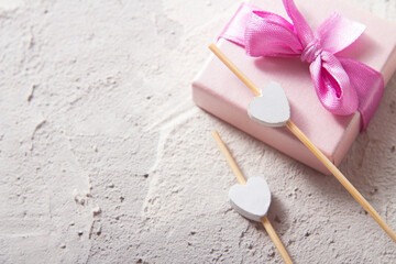 Fototapeta na wymiar Gift box with a ribbon closeup and two wooden hearts Flat layout
