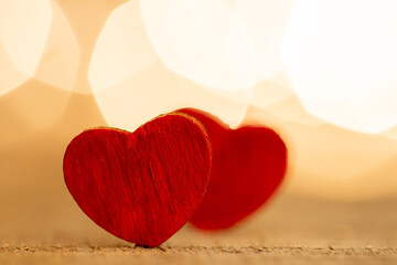 Valentine's Day greetings concept. Little red wooden heart close up, party lights bokeh on...