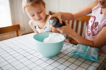 Funny children play with shaving foam and starch at home in the kitchen. Educational classes and...