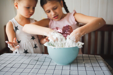 Funny children play with shaving foam and starch at home in the kitchen. Educational classes and...