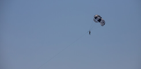 Parasailing is a popular type of outdoor activity at the sea. Parachute soars in the sky over the Sea with tourists