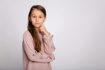 Obraz premium Portrait of a happy smiling child girl. Cute 8 years old girl face expression wearing pink sweater isolated over gray background