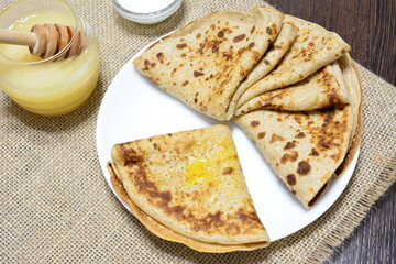 blini on white plate with honey and sour cream on burlap texture background
