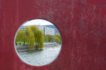 View through a hole of a red bridge balustrade in Zurich, Switzerland: A park situated at the...