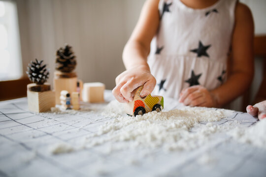 Funny children play with artificial snow at home in the kitchen. Educational classes and experiments with children at home. Sensory development and games at home. Snow from starch and shaving foam