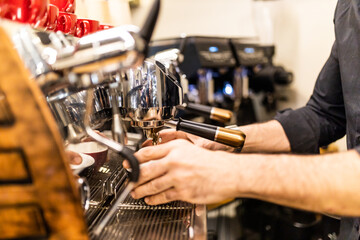 Fototapeta na wymiar unrecognizable barista making espresso coffee in his coffee machine in a coffee shop
