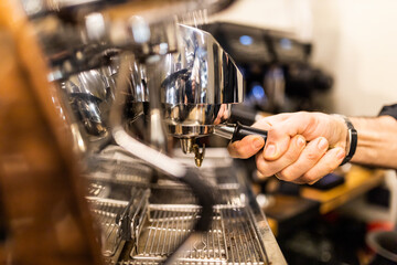 unrecognizable barista making espresso coffee in his coffee machine in a coffee shop