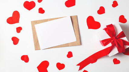 Blank card, envelope, paper hearts and gift box on white background, flat lay with copy space. Valentine's Day celebration. Romantic love letter for Valentine's day concept.
