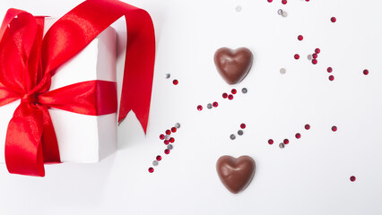 Gift with red bow and heart-shaped candles on the wooden background, Valentines