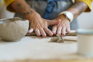 Ceramist working with raw clay. Closeup of pottery master hands shaping and molding wet earthenware while sculpturing pot cup or bawl. Workplace in ceramics studio or workshop. Art and small business