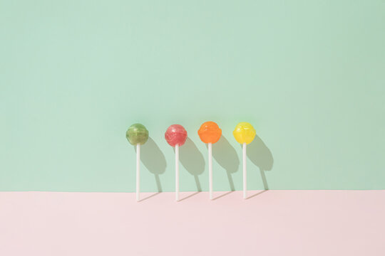 Colorful lollipops leaning against a green wall and a pink background. Minimal candy lay out concept
