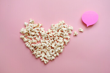 Pop Corn heart on pink background. Valentines day present cinema concept. Top view flat lay with copy space. Place for idea, quote or film title