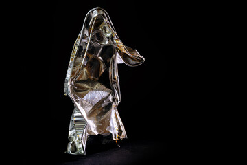 Aluminum foil tray of convenience food shown like a human art sculpture against a black background,...