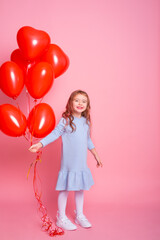 Beautiful child girl with red heart romantic balloons on pink background. Concept of Valentine day