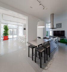 Modern white interior of spacious private house. Kitchen dinner room.