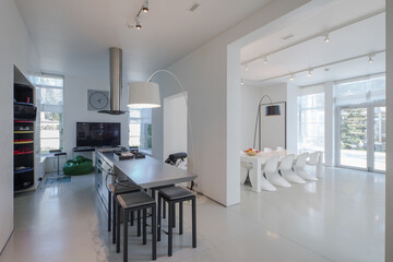 Modern white interior of spacious private house. Kitchen dinner room.