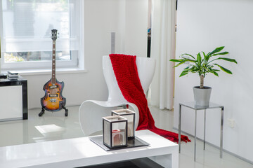 White interior of luxury apartment. Chair, guitar, plant, candles.