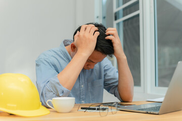 A male engineer sitting in the office is stressed.