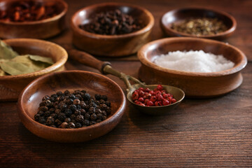 Various spices in small wooden bowls on a dark brown rustic table, food concept, selected focus
