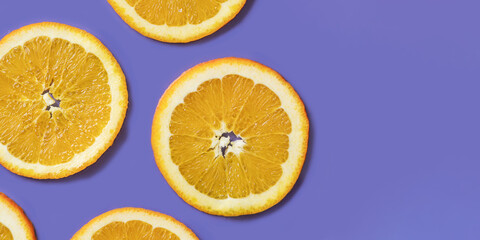 Sliced fruit oranges in checkered pattern on violet background. Fruit background from a slice of oranges. Demonstrating very peri, color of 2022 year.