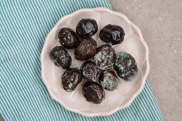 top view moldy inedible black olives on plate