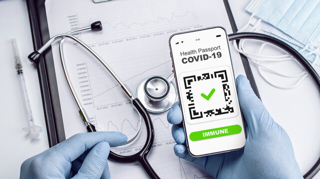 Covid passport doctor holding. Coronavirus vaccination certificate of immunity passport on smartphone screen with doctor stethoscope, syringe and medical equipment on hospital white background. - Powered by Adobe