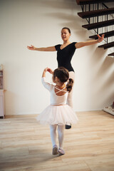 Young mother and 3 years old daughter dancing classical ballet at home