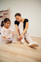 Young mother and 3 years old daughter dancing classical ballet at home