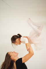 Young mother and 3 years old daughter dancing classical ballet at home