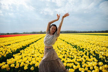 Dancing girl in a flower field full of yellow tulips in the Netherlands