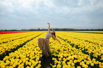 Dancing girl in a flower field full of yellow tulips in the Netherlands