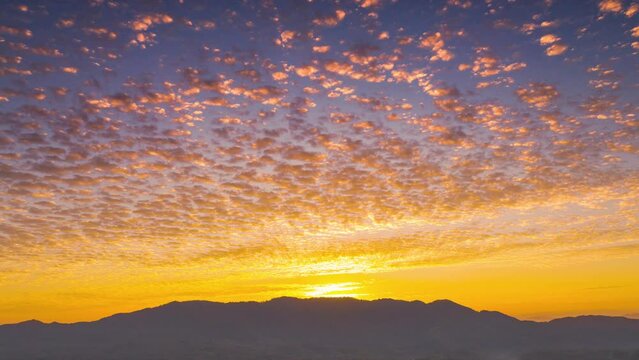 4K time-lapse video motion. Beautiful of morning orange gold sky cloudscape over fertile forest mountains. Pang Puai, Mae Moh, Lampang, Thailand.	