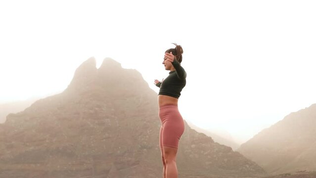 Young woman doing fitness exercises at sunrise or sunset on the beautiful island with mountains and ocean