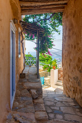 Obraz premium Traditional cycladitic alley with narrow street, typical houses and a blooming bougainvillea, in ano Syros Greece 